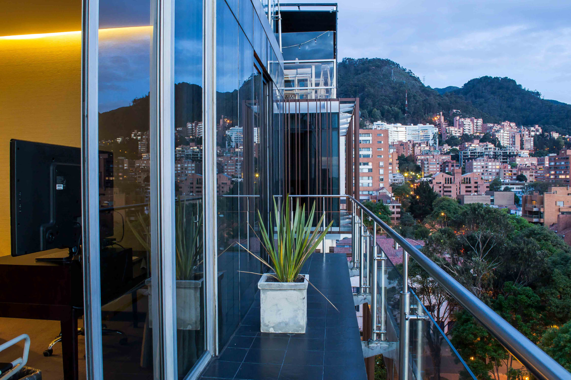 The suite's private balcony at dusk overlooking north Bogotá and the eastern hills