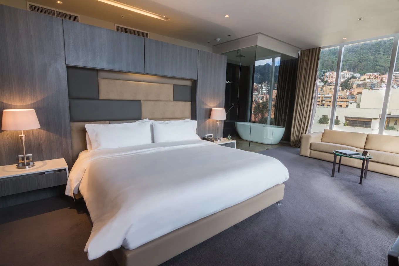 A five-star hotel suite in Bogotá with a king bed and floor-to-ceiling views of the city and eastern hills